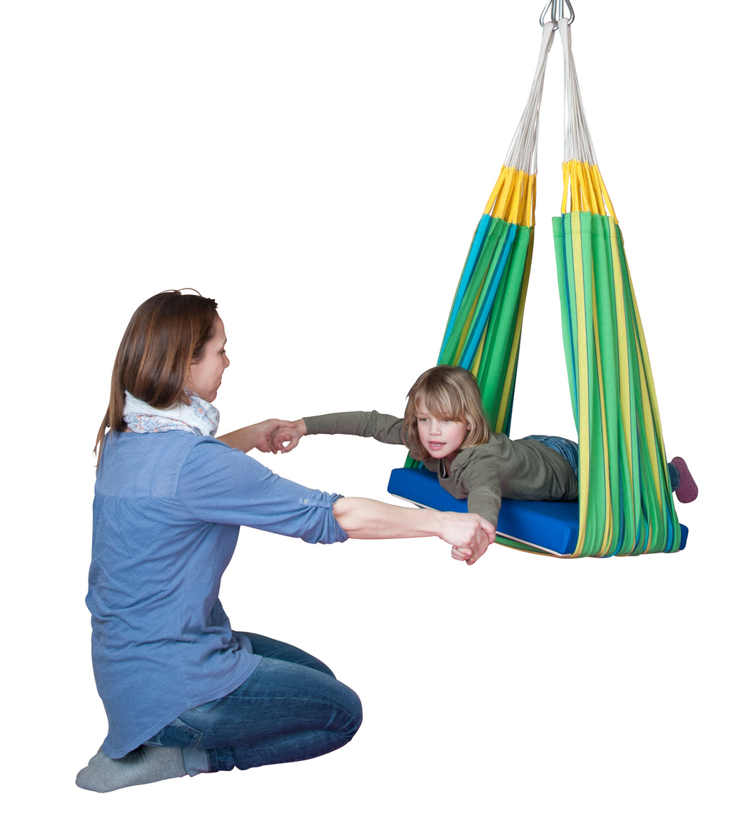 Do-it-yourself therapy platform swing made with a green hammock and a board. An adult is on her knees holding hands of a girl who is using the therapy platform swing