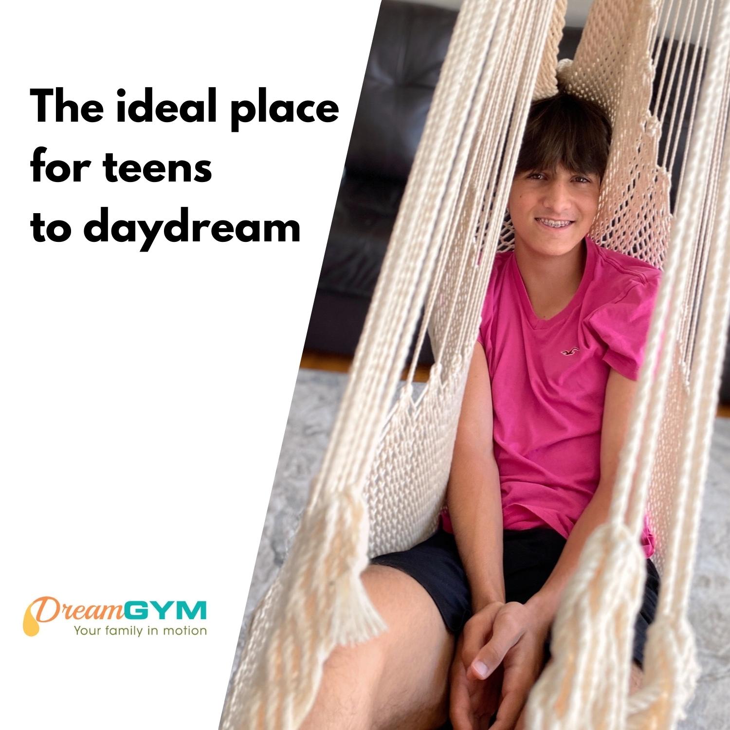 A teenage boy is resting in a hammock swing. The ideal place for teens to daydream. Hammock chair is in cream colour.