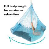 A woman is resting in a blue hammock that supports her full body for maximum comfort