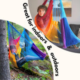 The rainbow hammock swing is great for indoors and outdoors. A girl is swinging in a hammock in a living room and a boy is using a hammock swing in the forest. 