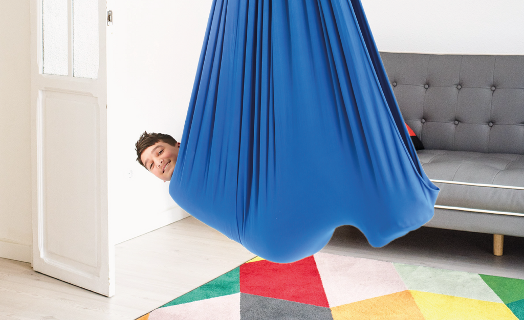 A boy is using a blue sensory swing
