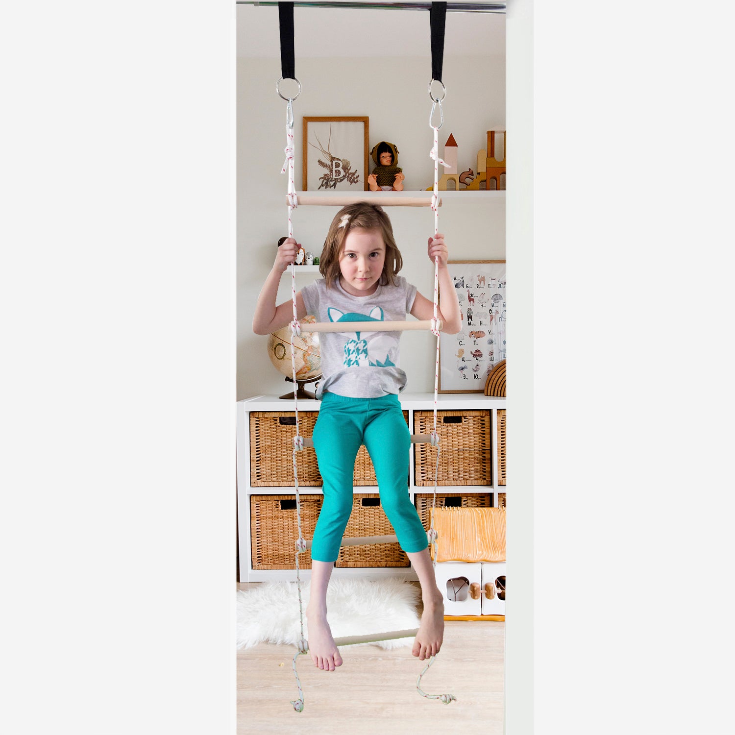 A girl is playing on a rope ladder installed in a doorway