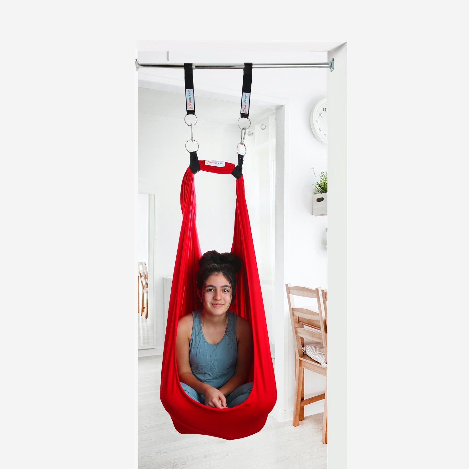 A teen girl is sitting in a doorway sensory swing in red colour