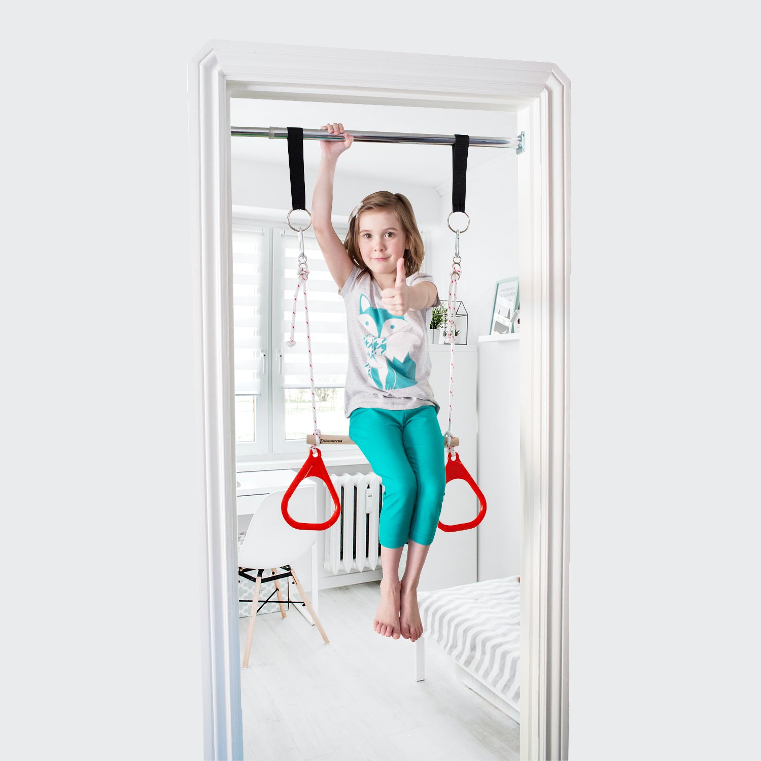 DreamGM Doorway Swing. A girl is using a doorway trapeze bar and gymnastics rings