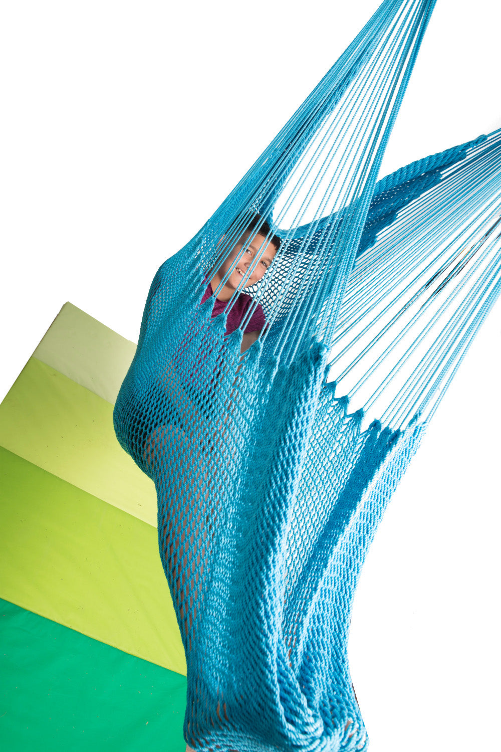 a teenage boy is resting in a blue hammock swing