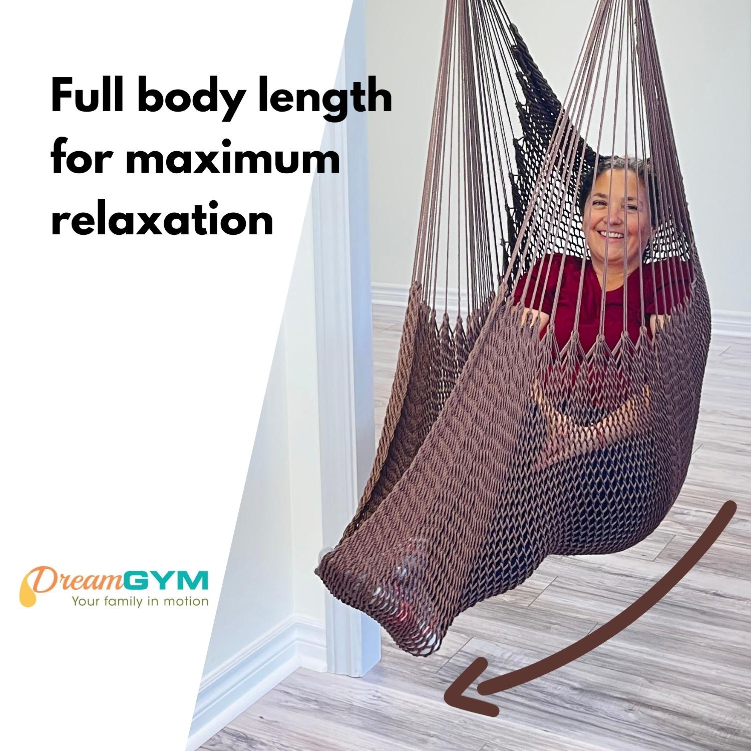 A woman is sitting in a brown hammock swing, that supports full body length for maximum relaxtion.