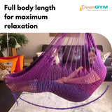 A woman is resting in a hammock swing. It provides full body length for maximum relaxation. Beautiful violet colour.