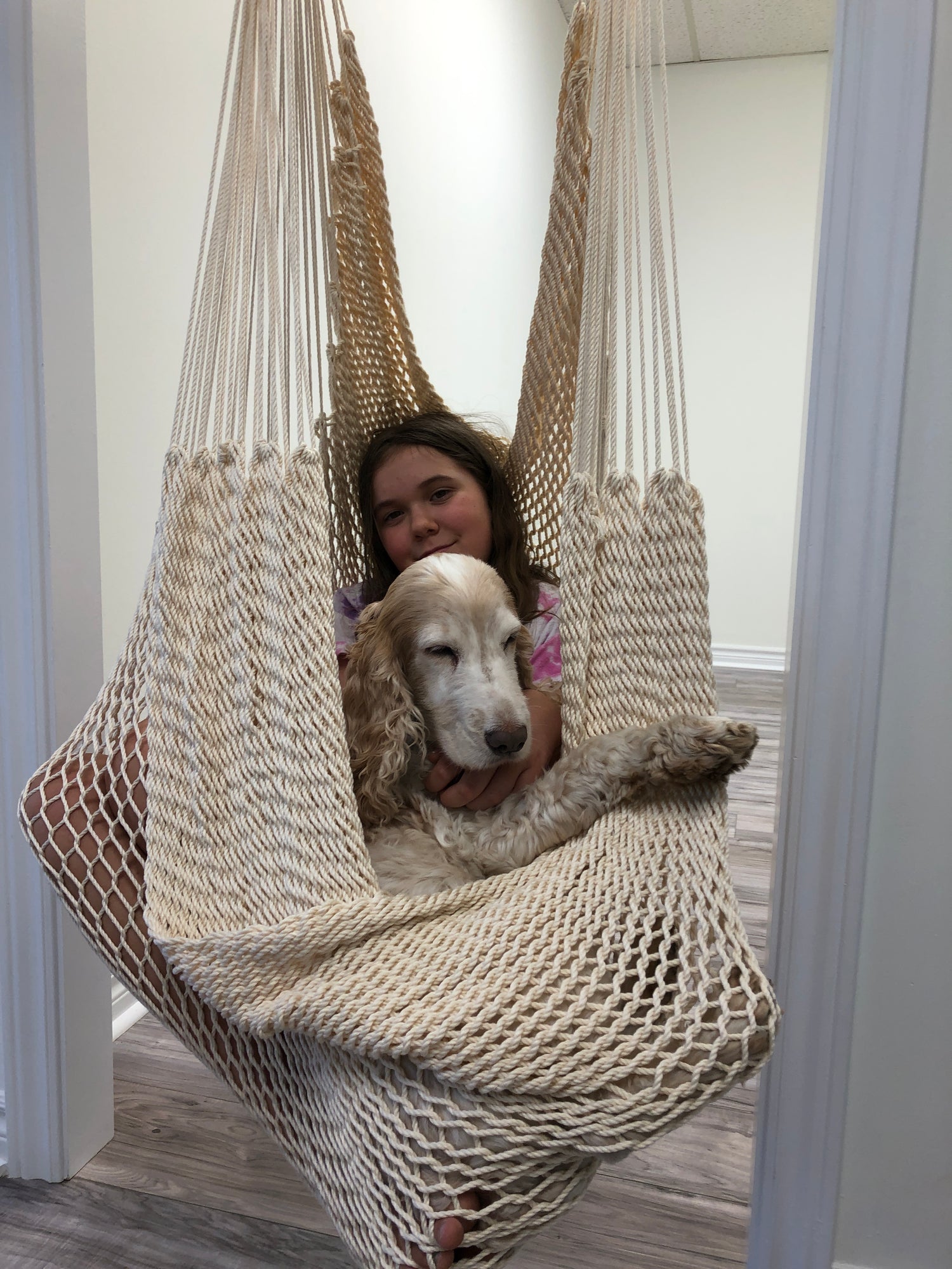 A girl and her puppy are enjoying sitting in a Therapy Hammock Swing - Soft Ivory - DreamGYM