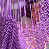 A tired girl is relaxing in a purple hammock swing.