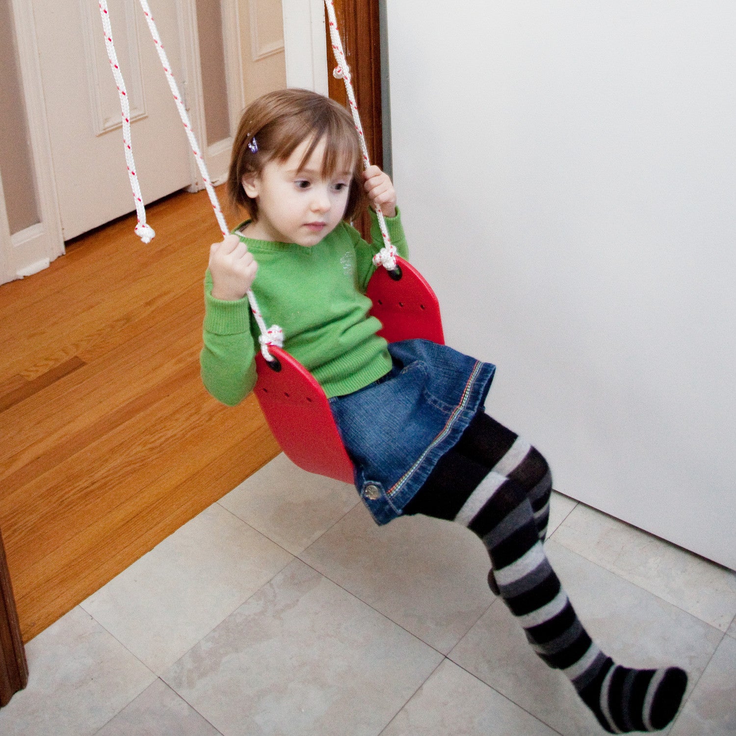 a girl is using a doorway swing